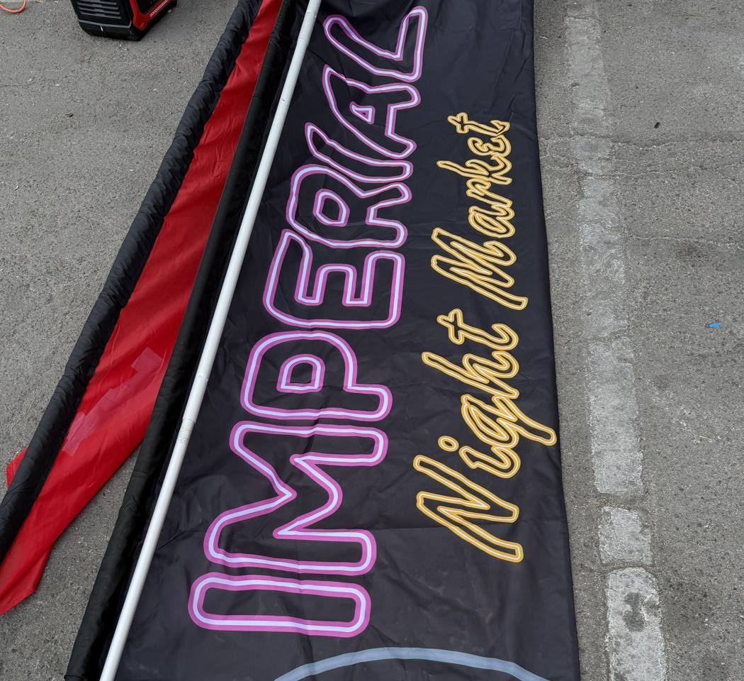 The Imperial Night Market flag banner lying on the ground